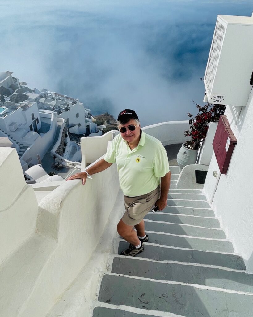 Greece Best Place to Visit: Cos walking up stairs of white building in Santorini