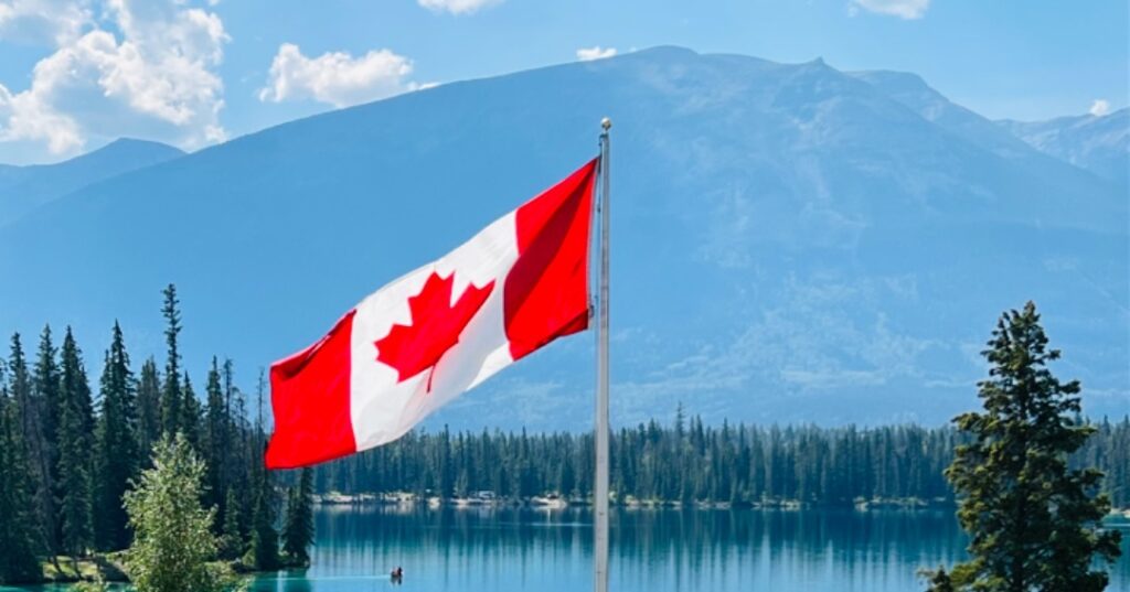 Canadian flag against lake and large hill