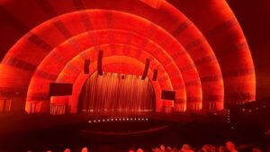 Red-lit theater stage with curtain and speakers