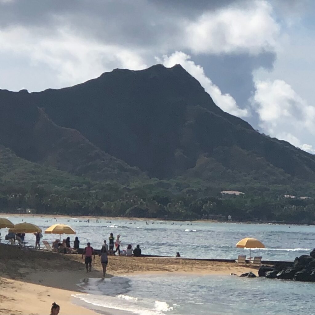 Mountain with water and beach and beach umbrellas