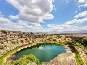 Desert oasis under cloudy sky and bright sunlight.