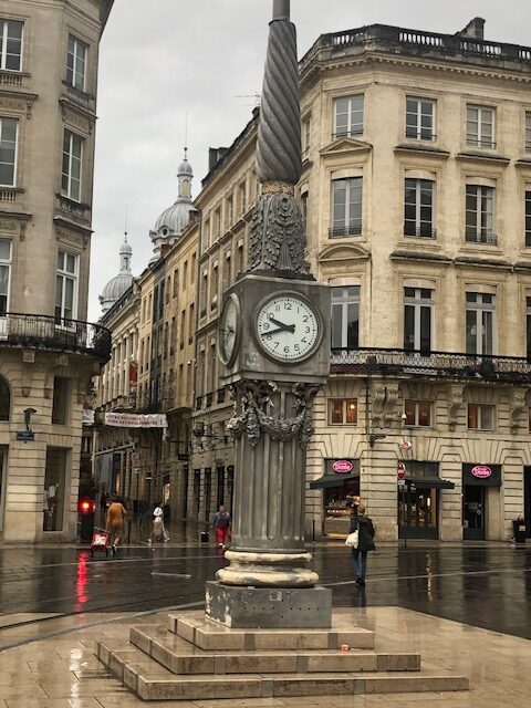 Ornate street clock in rainy city square.