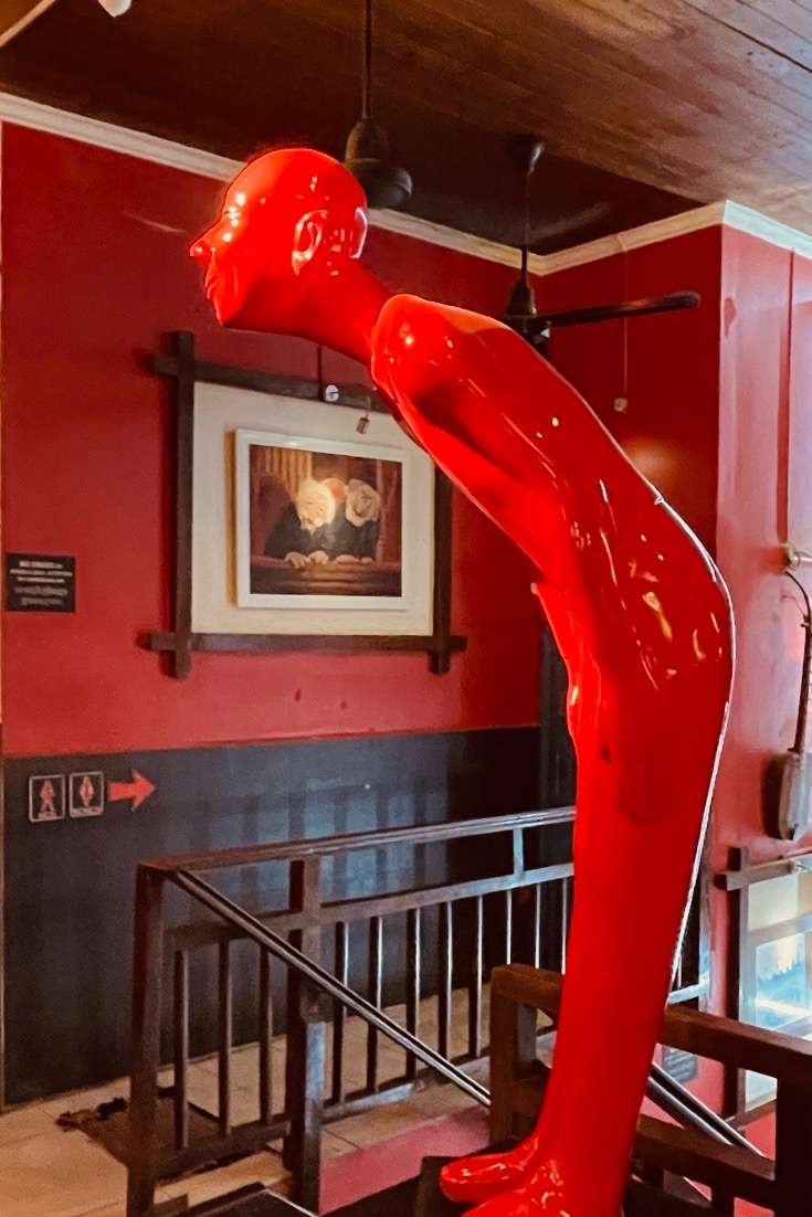 Cambodia Night Life: red statue of man bending over