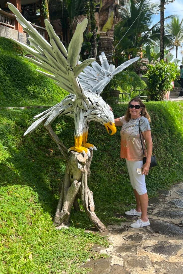 Things to Do in Bali, Indonesia: Robin standing with wooden eagle statue