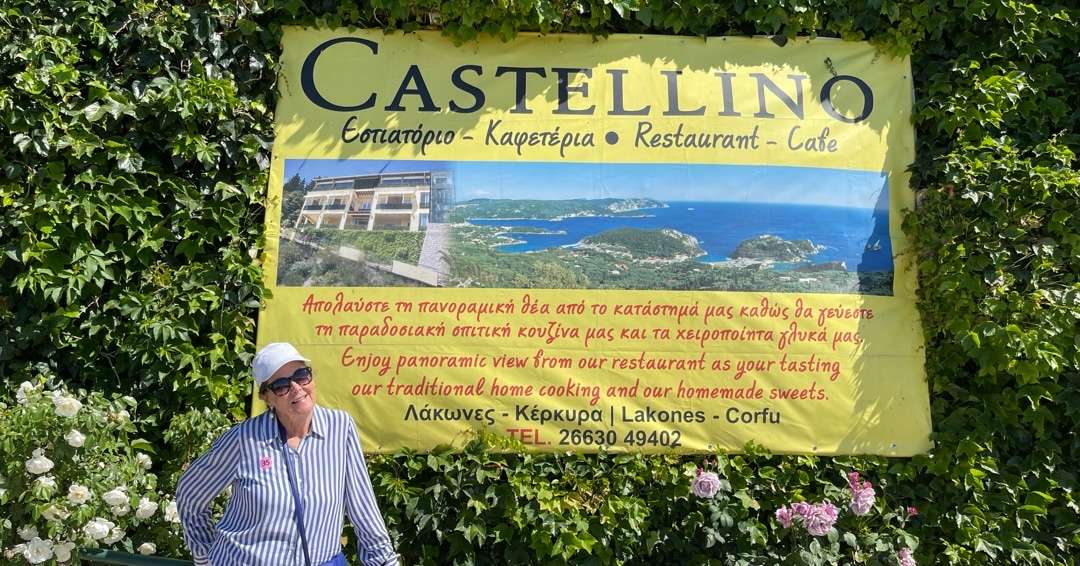 Robin in front of sign for Castellino in Corfu