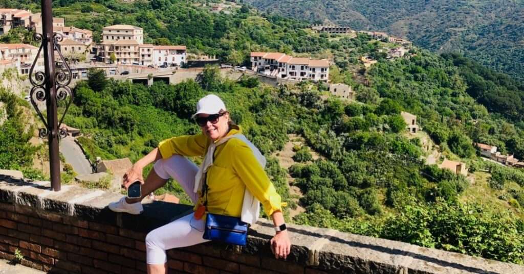 Robin sitting on a wall overlooking a valley during our Sicily Travel Itinerary
