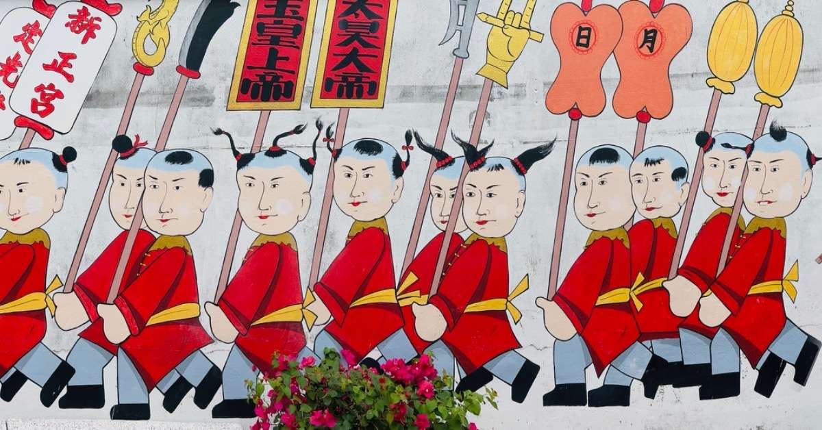 Street art in Phuket of 12 Chinese people all dressed in red with yellow belts, carrying various posts