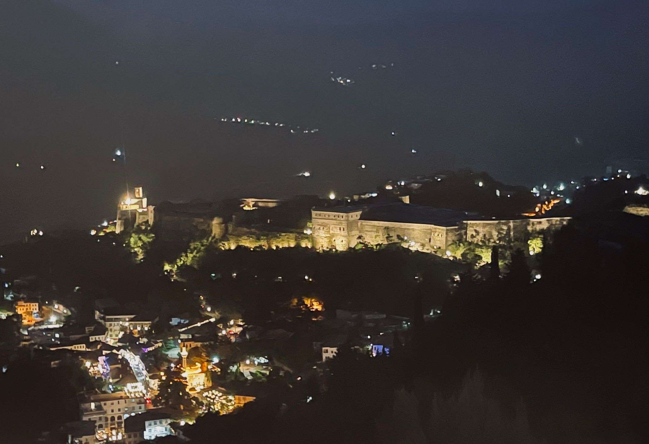 Nighttime view of Gjirokastra, Albania showing the lighted walled city and the town outside