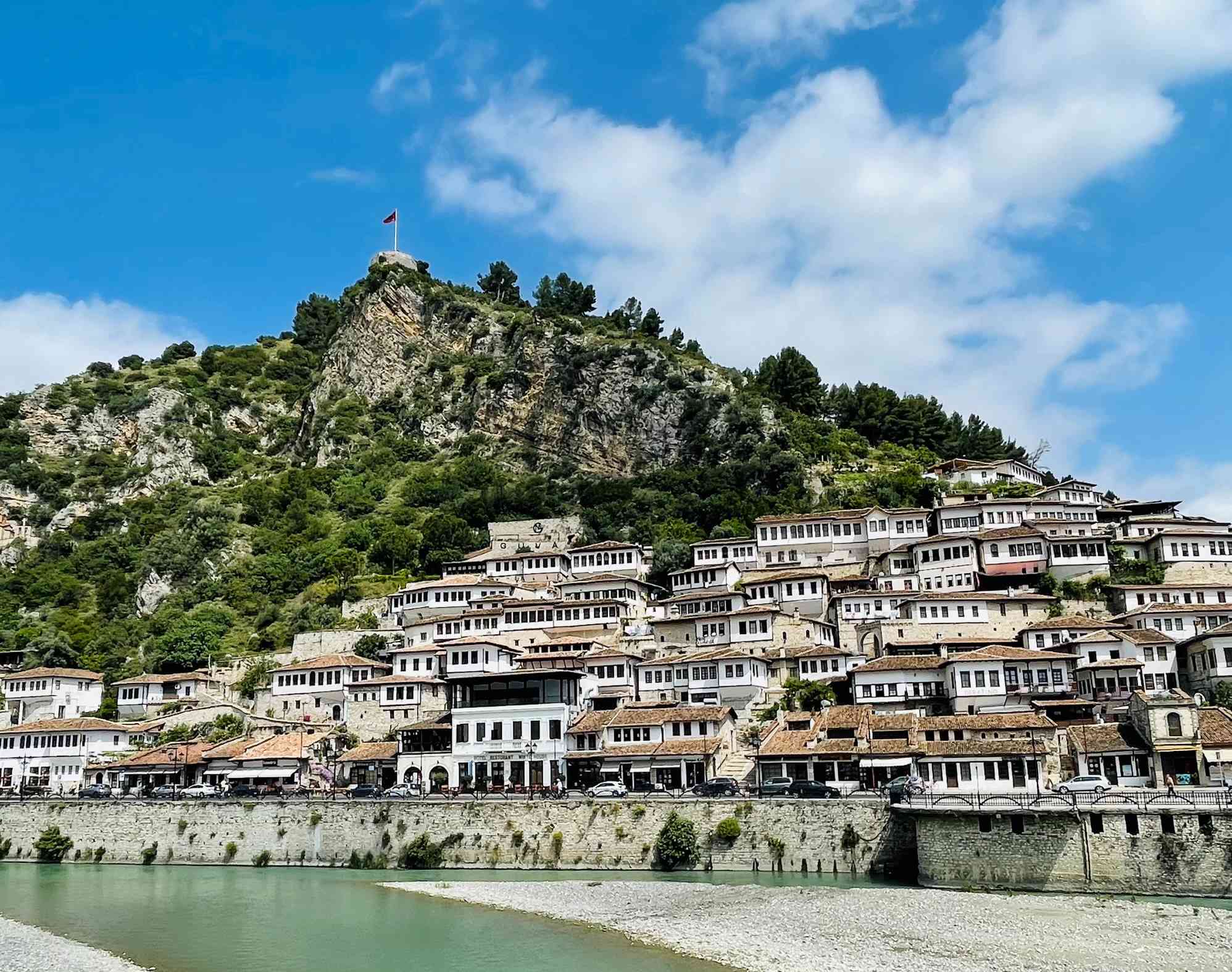 City of windows Berat below a hill with a castle and flag flying in Albania