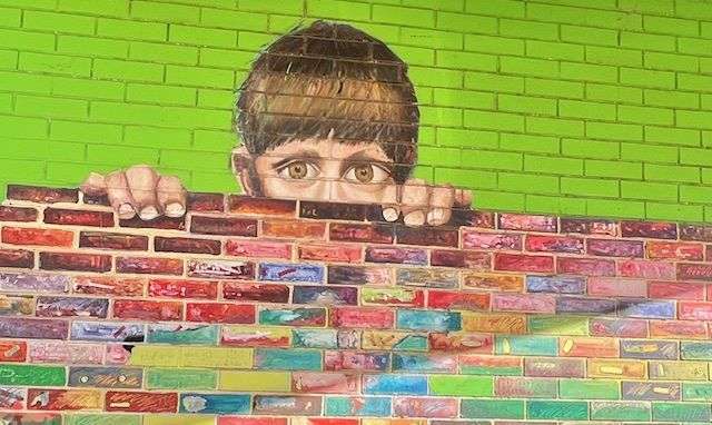 Young man looking over a wall graffiti art