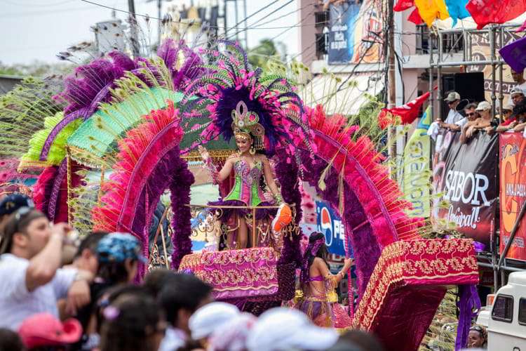 People watching multi-colored floats with Carnival Queen waving to the crowds during Carnival in Panama City