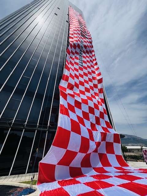 Red and white checkerboard pattern on long draped fabric over a dark grey hotel in Split Croatia