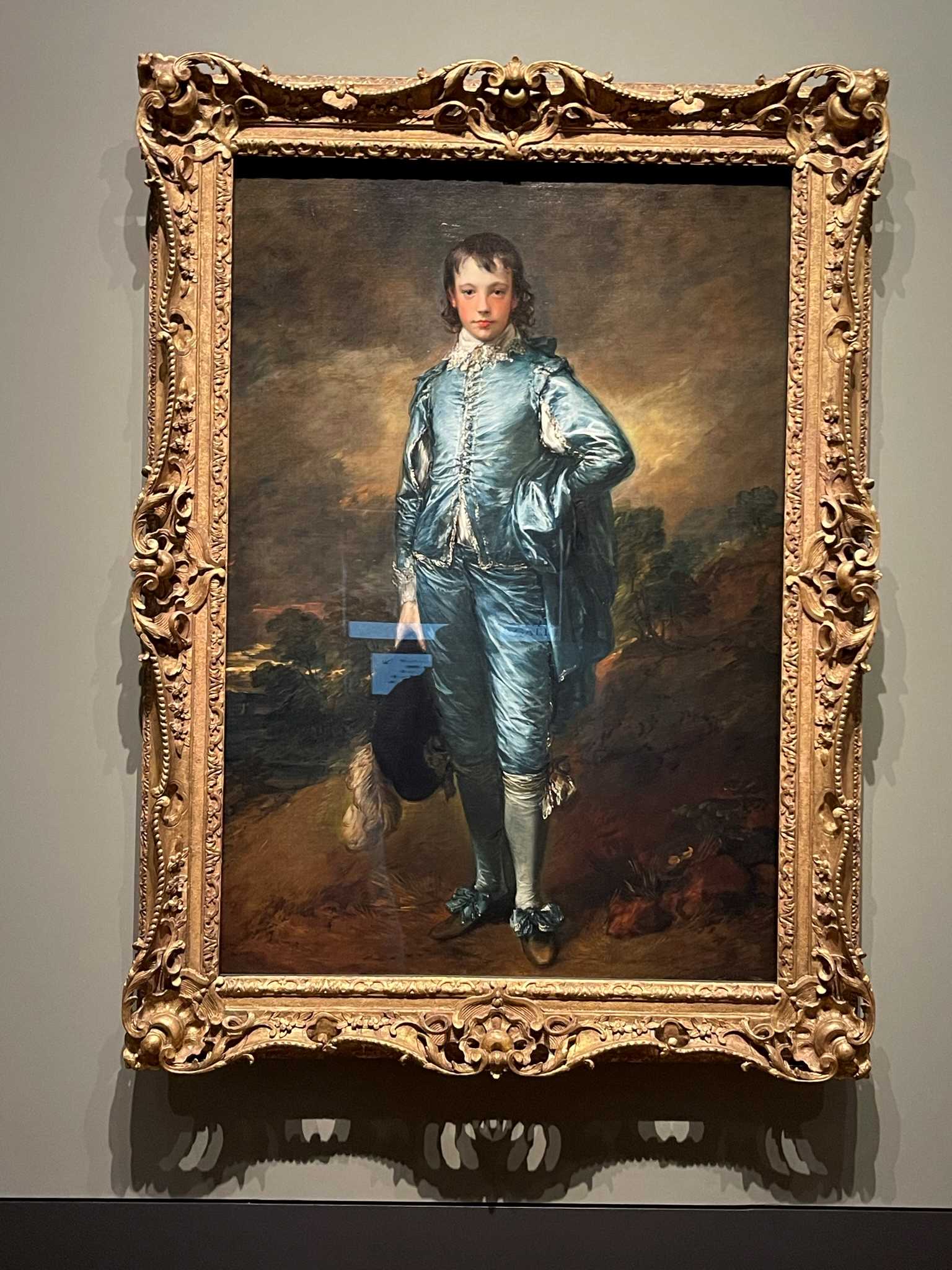 Painting with elaborate frame of a young boy in blue outfit in London museum