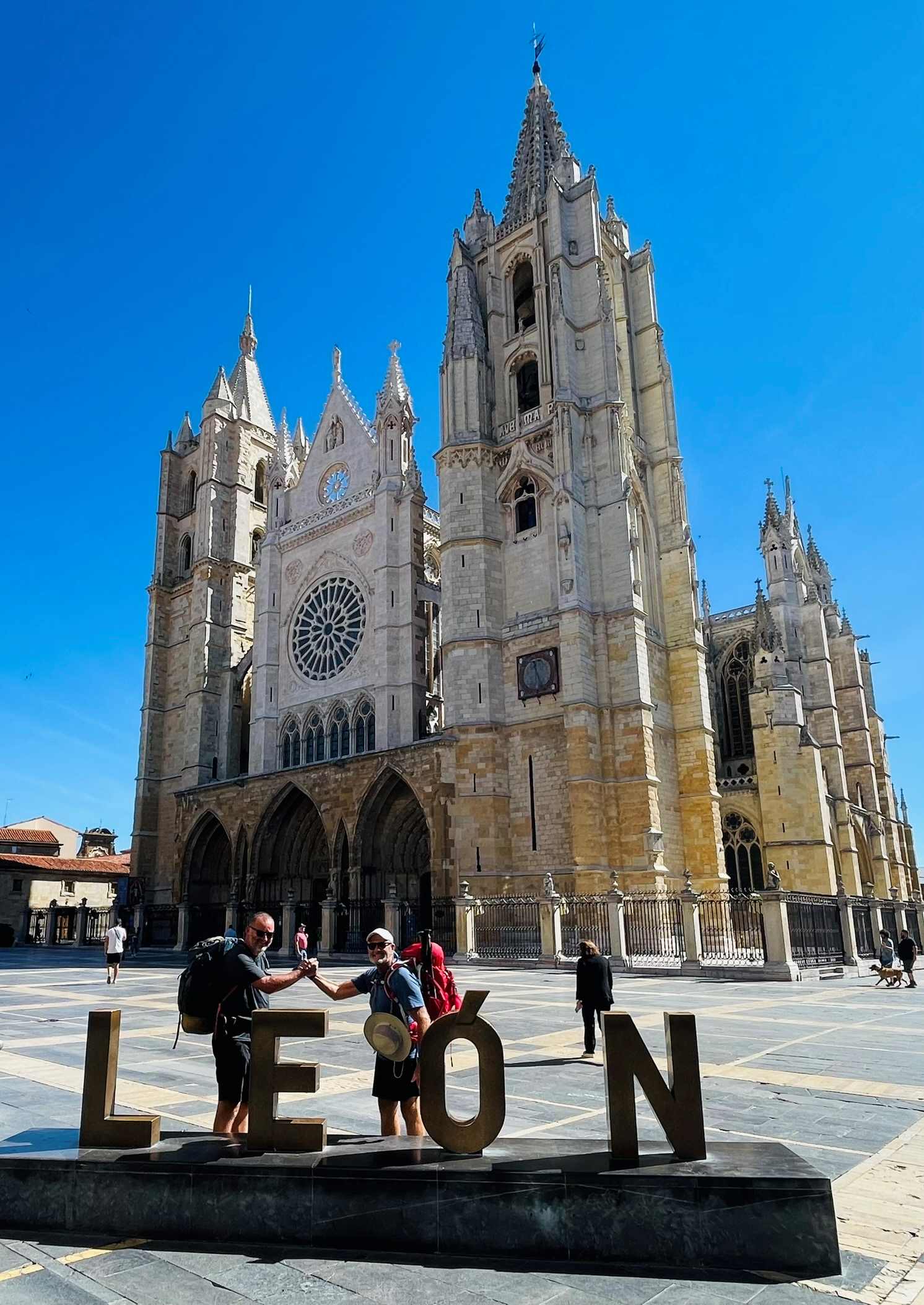 Photograph of large cathedral with letters LEON in front along with two men shaking hands in Leon, Spain