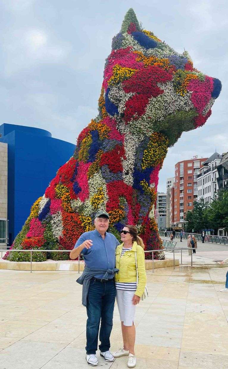 Couple posing by colorful flower sculpture of a cat