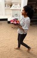 Woman walking with flowers in sandy courtyard to one of the Buddhist Temples in Sri Lanka.