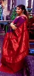 Woman in red saree standing on street.