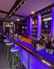 Modern bar with neon lights and bottles display.