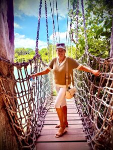 Woman standing on a rope bridge, smiling.