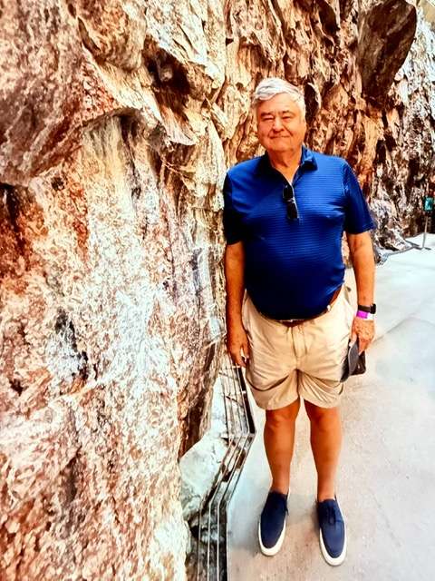 Man standing next to rocky wall.