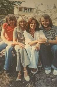 Four people sitting outdoors, smiling together.