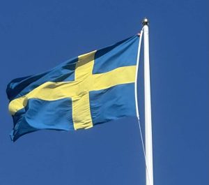 Swedish flag waving against clear blue sky. Sweden vs Finland