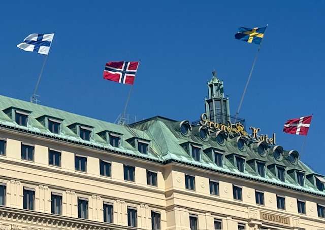 Nordic flags atop Grand Hôtel building rooftop; Stockholm to Helsinki