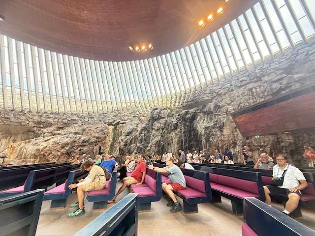 Visitors inside rock-walled, modern dome building.