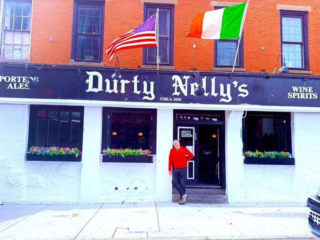 Person outside Durty Nelly's pub with flags displayed.