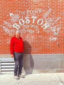 Man stands by Boston wall art mural.