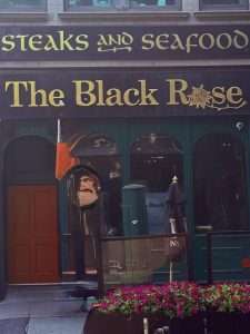 The Black Rose pub entrance with flower display.