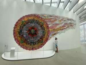 Colorful circular art piece with flowing tail design.