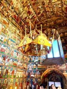 Colorful church frescoes with ornate chandelier.