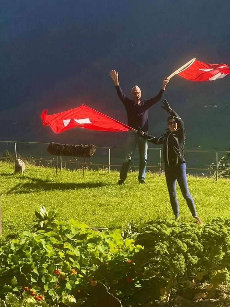 Two people waving flags in garden.