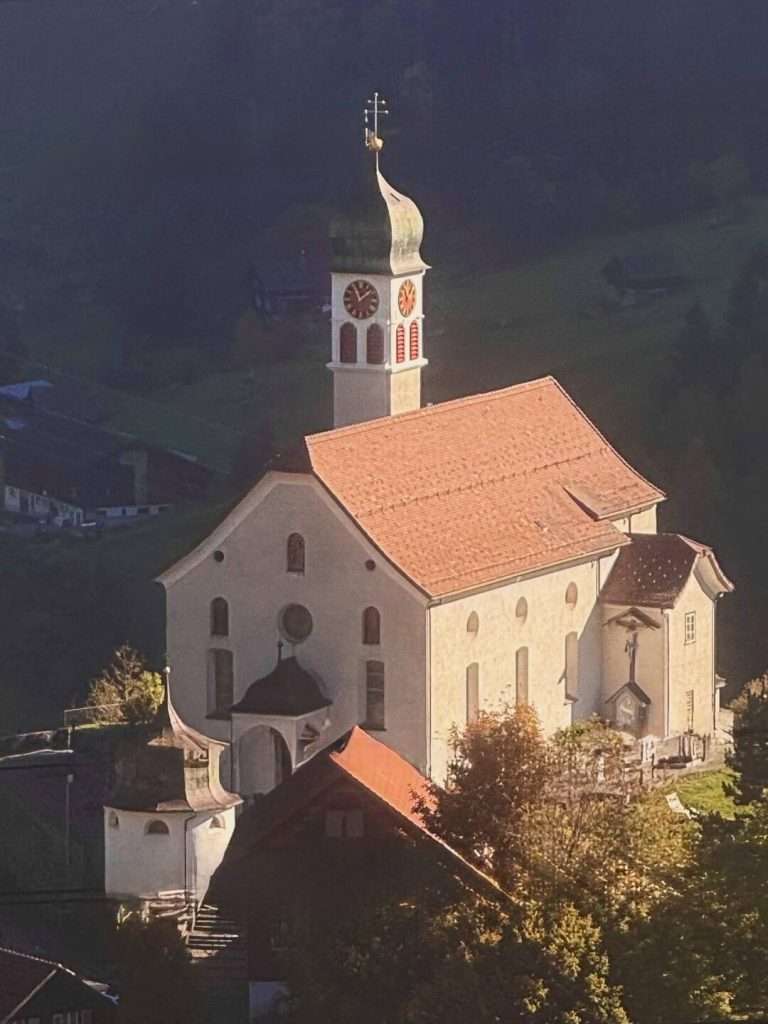 Historic church with clock tower in countryside landscape.