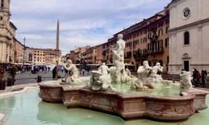 Fountain in Piazza Navona, Rome with statues and people.