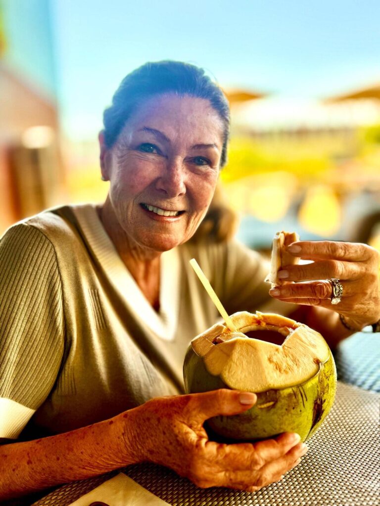 Smiling woman holding coconut with straw.