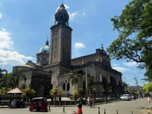 Historic cathedral with clock tower and people nearby.