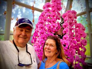 Smiling couple in garden with pink orchids.