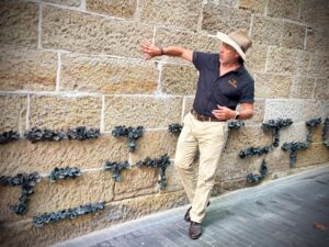 Man explaining textured stone wall with plants.