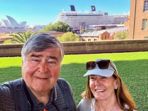 Couple posing with Sydney Opera House and cruise ship.