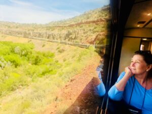 Woman gazing from train window, scenic landscape view.