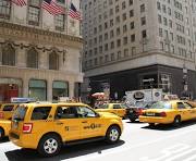 Yellow taxis on a city street with buildings.
