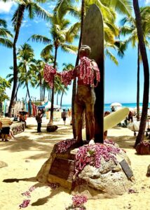 Statue with leis on sunny beach.