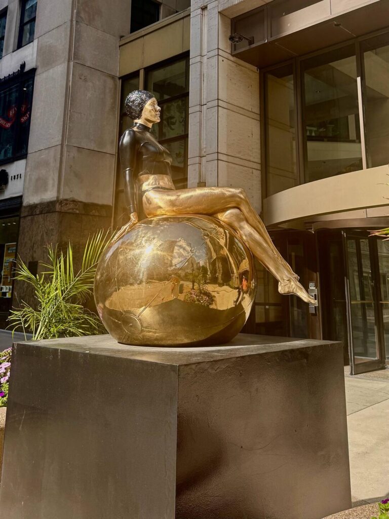 Gold statue of person sitting on globe.