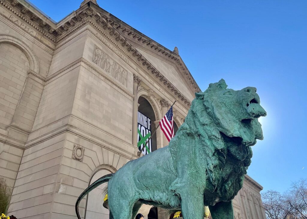 Lion statue at museum entrance with American flag.