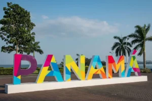 Colorful Panamá sign with trees and ocean backdrop.