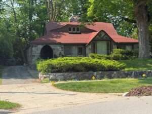 Stone house with red roof in wooded area.