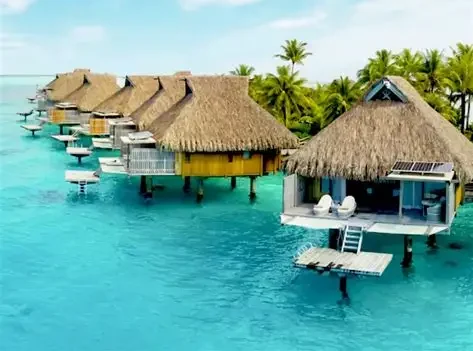 Overwater bungalows on tropical ocean, sunny day.
