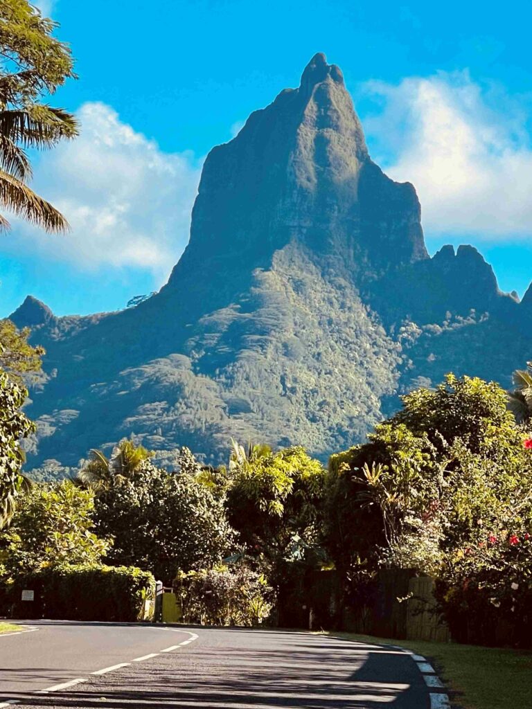 Mountain peak with lush greenery under blue sky.